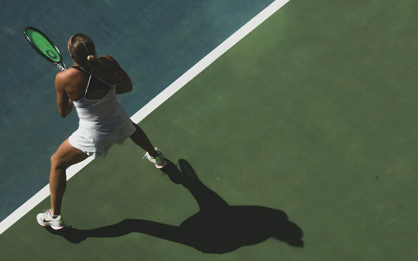 A tennis player mid-swing on a court, seen from above